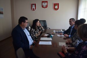 Kilka osób siedzących przy stole, na którym znajduje sie szereg dokumentów