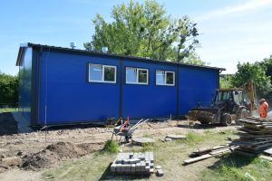 Niebieski budynek stacji uzdatniania wody, wokół budynku plac budowy
