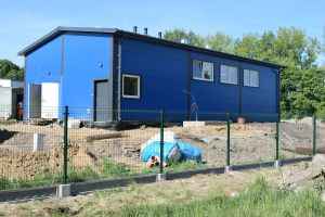Niebieski budynek stacji uzdatniania wody, wokół budynku plac budowy