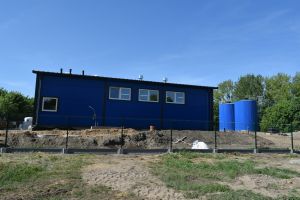 Niebieski budynek stacji uzdatniania wody, wokół budynku plac budowy