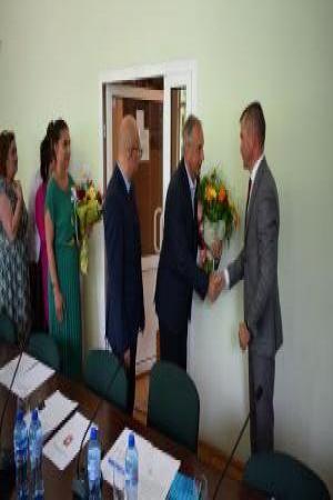 Grupka ludzi składa życzenia życzenia i wręcza kwiaty mężczyźnie