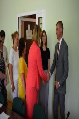 Grupka ludzi składa życzenia życzenia i wręcza kwiaty mężczyźnie