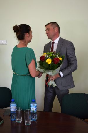 Młoda kobieta w zielonej sukience składa życzenia i wręcza kwiaty mężczyźnie