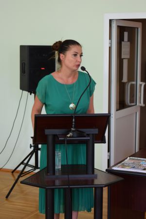 Kobieta w zielonej sukience, przemawia stojąc na mównicy