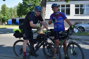 Dwóch rowerzystów stojących przy rowerach i pozujących do zdjęcia