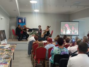 Scena, na której występuje czwórka skrzypków oraz zgromadzona publiczność