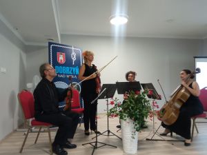 Czwórka skrzypków na scenie, grających koncert