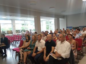 Publicznosć siedząca w przestronnej sali, oglądajaca koncert