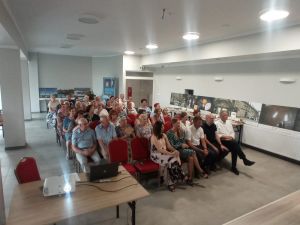 Publicznosć siedząca w przestronnej sali, oglądajaca koncert