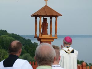 Grupa duchownych stojaca przy drewnianej figurze, przedstawiającej postać Św. Jakuba