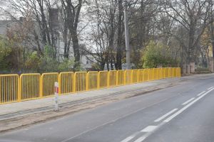Chodnik, na nim zainstalowane żółte barierki zabezpieczające