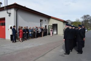 Grupa strażaków i ludzi stojaca przed wyremontowanym budynkiem świetlicy wiejskiej