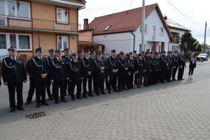 Grupa strażaków stojąca przed budynkiem nowo wyremontownej świetlicy wiejskiej