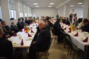 Spora grupa osób siedząca za zastawionymi stołami w przestronnej sali