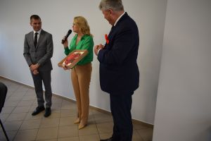 Kobieta i dwóch mężczyzn przemawiaja do siedzących za stołami ludźmi