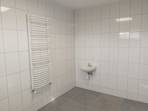 Fragment wyremontowanych miejsc prysznicowych, ujęcie nowej glazury w kolorze jasno brązowym