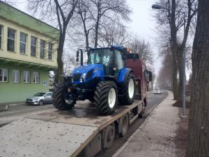 Niebieski ciągnik New Holland na pojeździe transportującym