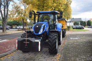 Niebieski ciągnik stojący przed budynkiem Urzędu Gminy