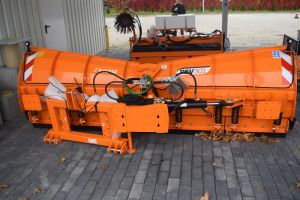 Pomarańczowa odśnieżarka stojąca pod wiatą