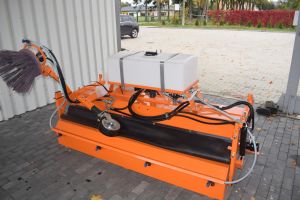 Pomarańczowa zamiatarka do ulic stojąca pod wiatą