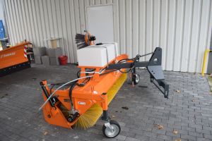 Pomarańczowa zamiatarka do ulic stojąca pod wiatą