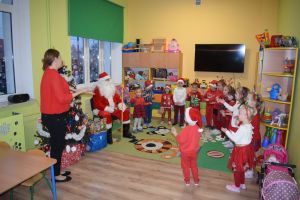 Mikołaj odwiedzający uczniów i przedszkolaków i częstujący ich słodyczami z czerwonego worka