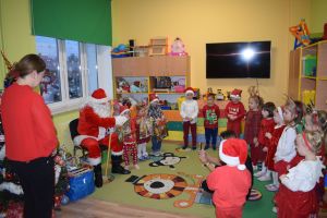 Mikołaj odwiedzający uczniów i przedszkolaków i częstujący ich słodyczami z czerwonego worka