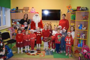 Mikołaj odwiedzający uczniów i przedszkolaków i częstujący ich słodyczami z czerwonego worka