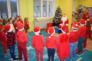 Mikołaj odwiedzający uczniów i przedszkolaków i częstujący ich słodyczami z czerwonego worka