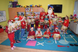 Mikołaj odwiedzający uczniów i przedszkolaków i częstujący ich słodyczami z czerwonego worka