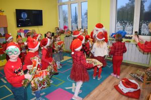 Mikołaj odwiedzający uczniów i przedszkolaków i częstujący ich słodyczami z czerwonego worka