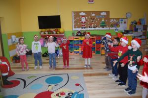 Mikołaj odwiedzający uczniów i przedszkolaków i częstujący ich słodyczami z czerwonego worka