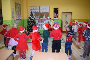 Mikołaj odwiedzający uczniów i przedszkolaków i częstujący ich słodyczami z czerwonego worka