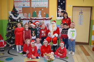 Mikołaj odwiedzający uczniów i przedszkolaków i częstujący ich słodyczami z czerwonego worka