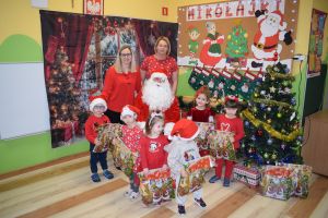 Mikołaj odwiedzający uczniów i przedszkolaków i częstujący ich słodyczami z czerwonego worka