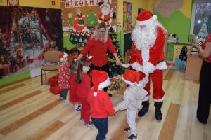 Mikołaj odwiedzający uczniów i przedszkolaków i częstujący ich słodyczami z czerwonego worka