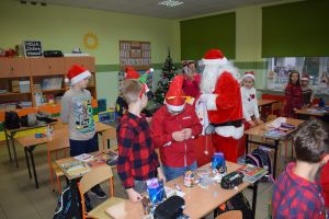 Mikołaj odwiedzający uczniów i przedszkolaków i częstujący ich słodyczami z czerwonego worka