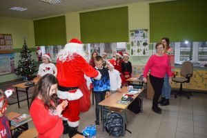 Mikołaj odwiedzający uczniów i przedszkolaków i częstujący ich słodyczami z czerwonego worka