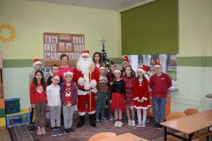 Mikołaj odwiedzający uczniów i przedszkolaków i częstujący ich słodyczami z czerwonego worka