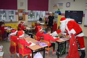 Mikołaj odwiedzający uczniów i przedszkolaków i częstujący ich słodyczami z czerwonego worka