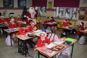 Mikołaj odwiedzający uczniów i przedszkolaków i częstujący ich słodyczami z czerwonego worka