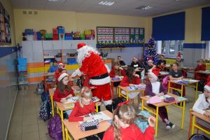 Mikołaj odwiedzający uczniów i przedszkolaków i częstujący ich słodyczami z czerwonego worka