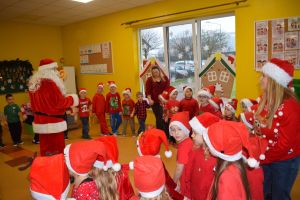 Mikołaj odwiedzający uczniów i przedszkolaków i częstujący ich słodyczami z czerwonego worka