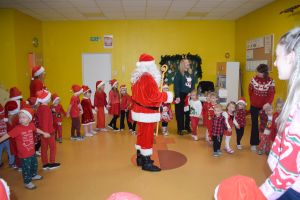 Mikołaj odwiedzający uczniów i przedszkolaków i częstujący ich słodyczami z czerwonego worka