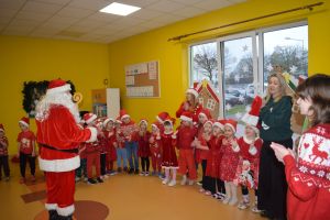 Mikołaj odwiedzający uczniów i przedszkolaków i częstujący ich słodyczami z czerwonego worka