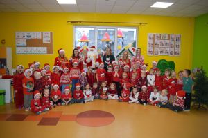 Mikołaj odwiedzający uczniów i przedszkolaków i częstujący ich słodyczami z czerwonego worka