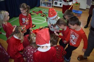 Mikołaj odwiedzający uczniów i przedszkolaków i częstujący ich słodyczami z czerwonego worka