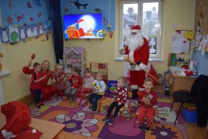 Mikołaj odwiedzający uczniów i przedszkolaków i częstujący ich słodyczami z czerwonego worka