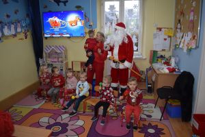 Mikołaj odwiedzający uczniów i przedszkolaków i częstujący ich słodyczami z czerwonego worka