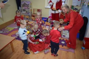 Mikołaj odwiedzający uczniów i przedszkolaków i częstujący ich słodyczami z czerwonego worka